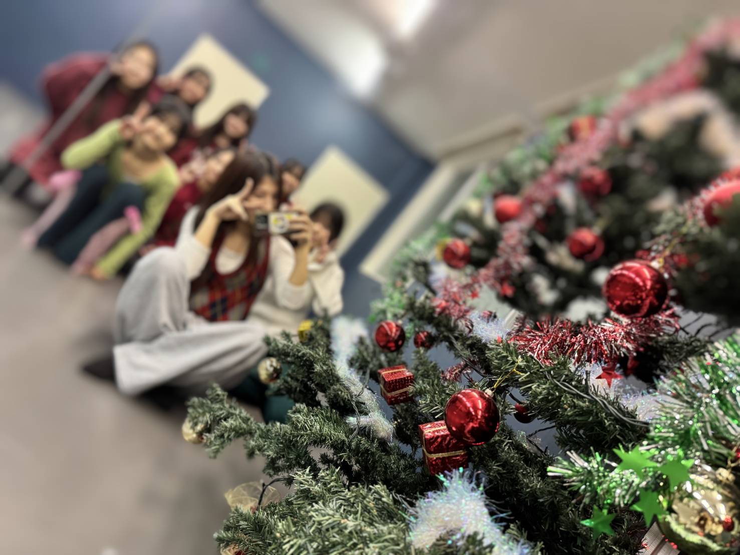 クリスマスの飾り付けをしたスタジオで、ピースサインをする生徒たち