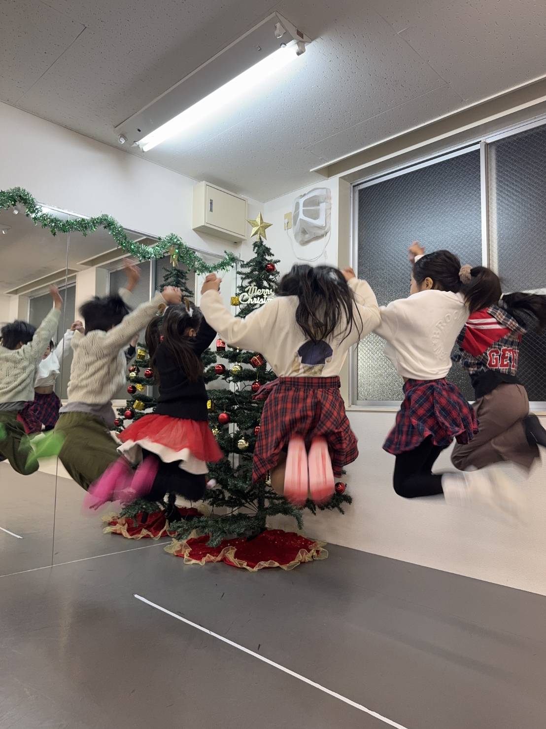 クリスマスツリーの前で、そろってジャンプする子どもたち